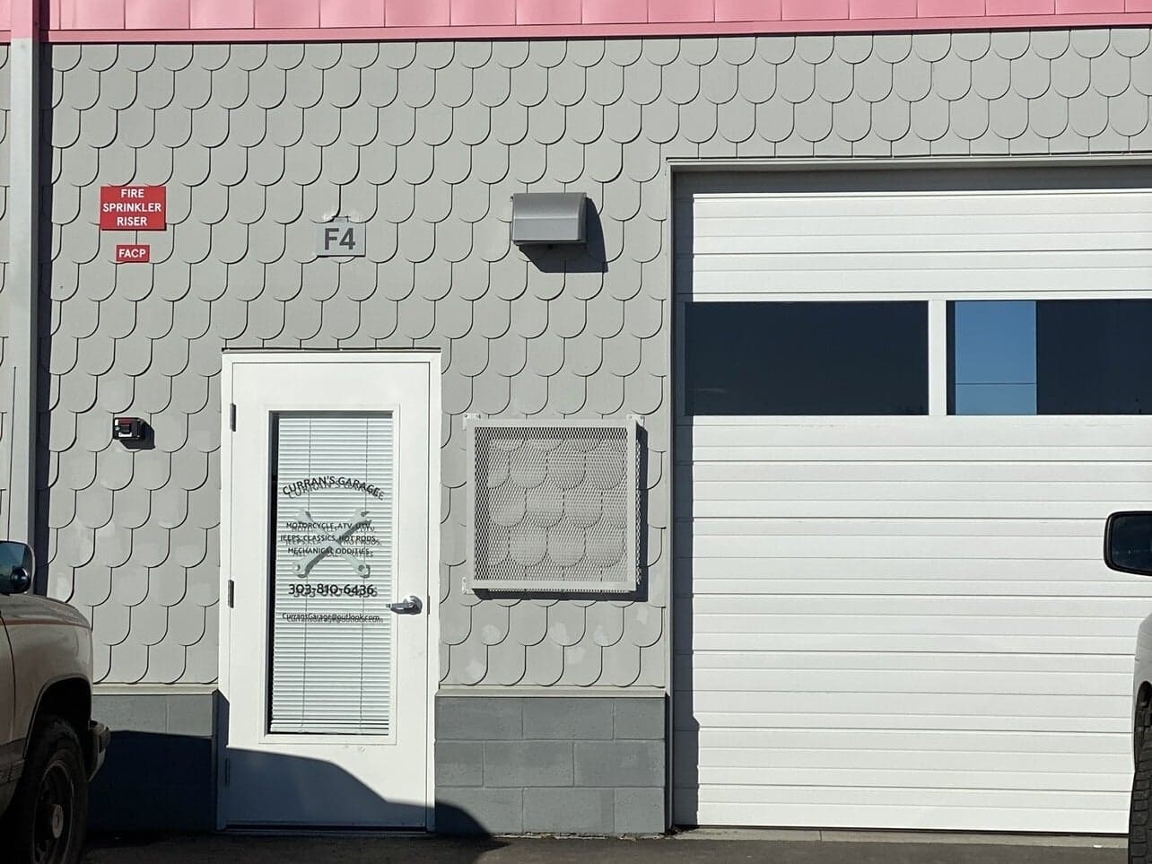 The shop door with the Curran’s Garage lettering, the services list and the F4 unit plate
